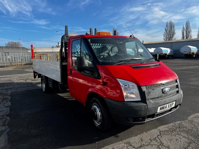 Ford Transit with flatbed, red colour in an industrial area of north east england.