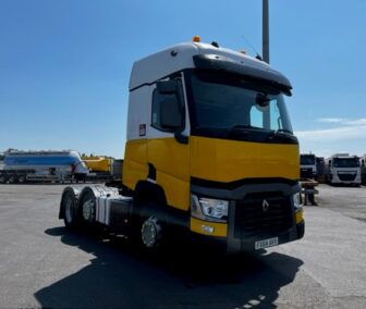 Yellow and white Renault truck with black front end, parked in an industrial lot.