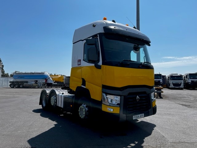 Yellow and white Renault truck with black front end, parked in an industrial lot.